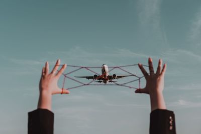 Midsection of person holding airplane against sky