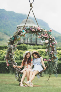 Full length portrait of smiling woman sitting against plants