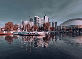 Sailboats moored in lake against buildings in city