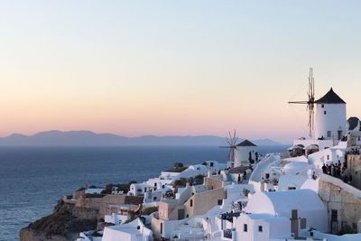 City by sea against sky during sunset