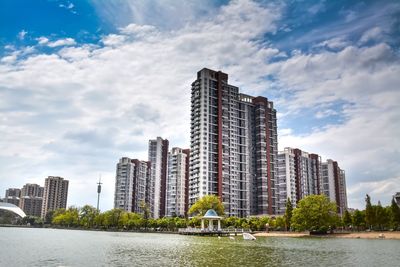 Buildings by river against sky in city