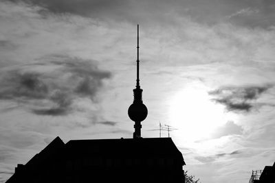 Low angle view of communications tower against cloudy sky