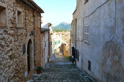 Narrow alley amidst buildings in town. old town of pollença, mallorca, spain.