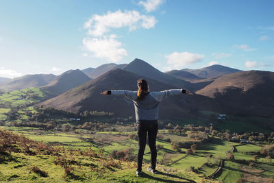 A girl standing in front of stunning mountain view, taking a deep breath.