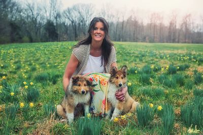 Portrait of smiling young woman with dog on field