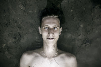 Portrait of shirtless young man lying down in water