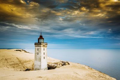 Lighthouse by sea against sky