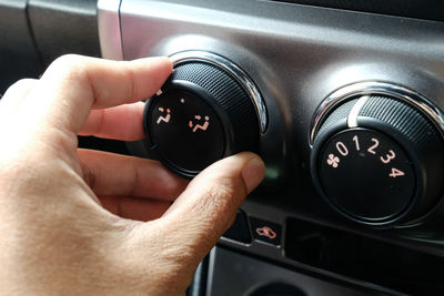 Cropped image of person adjusting knob of car air conditioner