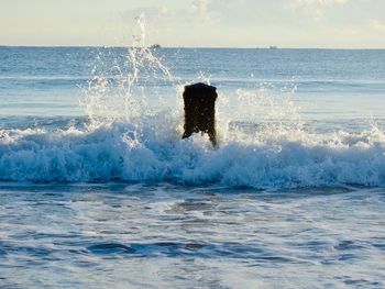 Water splashing in sea against sky