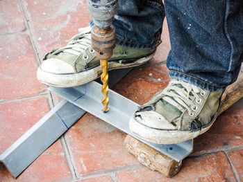 Low section of worker drilling metal on walkway 