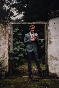 Portrait of young man standing against trees