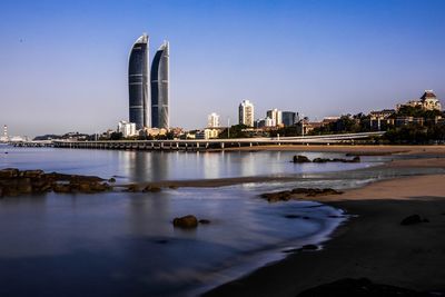 City at waterfront against blue sky