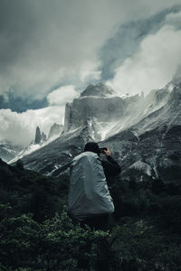 Rear view of man standing on mountain against sky