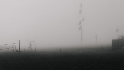 Electricity pylon on field against sky during foggy weather