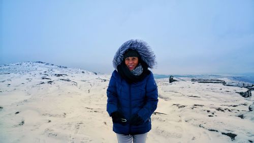 Portrait of woman standing on snow covered land against sky