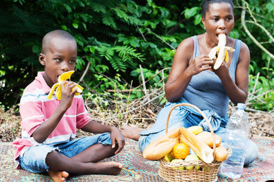 Young woman and her son eat bananas during a relaxing out