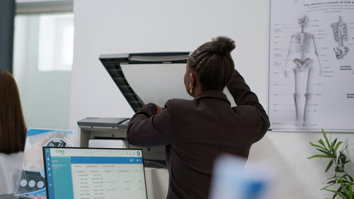 Rear view of woman using mobile phone in office