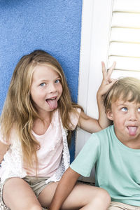 Portrait of girl with brother sticking out tongue
