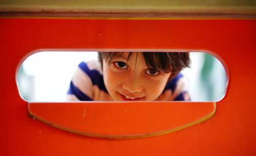 Close-up portrait of cute boy looking through outdoor play equipment