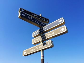 Low angle view of road signs against clear blue sky