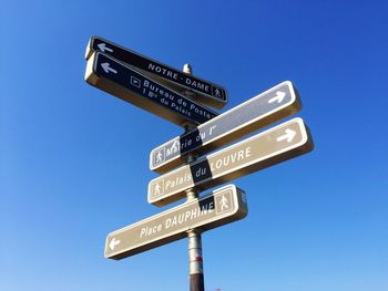 Low angle view of road sign against clear blue sky
