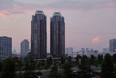 Modern buildings in city against sky during sunset