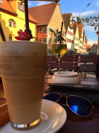 Coffee cup on table in cafe against buildings