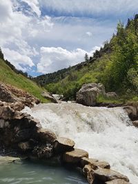 Scenic view of waterfall in forest against sky