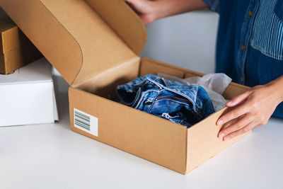 Closeup image of a woman receiving and opening a postal parcel box of clothing at home