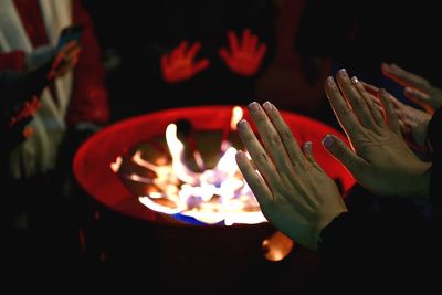 Cropped hands of woman by bonfire at night