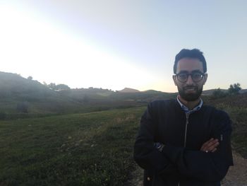 Portrait of young man standing on landscape against sky