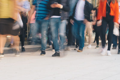 Low section of people walking on street in city