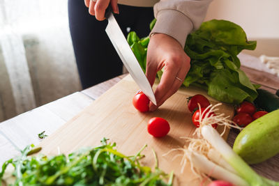 Cropped hand of man cutting vegetables on table