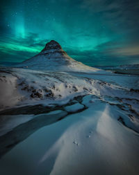 Scenic view of snowcapped mountains against sky at night