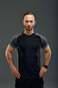 Portrait of young man standing against black background