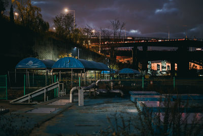 Illuminated bridge by buildings against sky at night