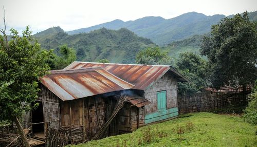 Old houses by field against mountains