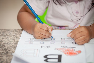 Midsection of girl tracing alphabet at home