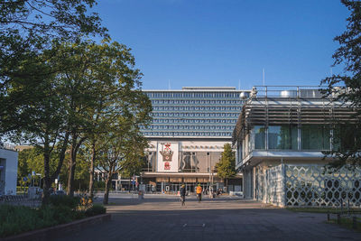 Street amidst buildings against clear blue sky