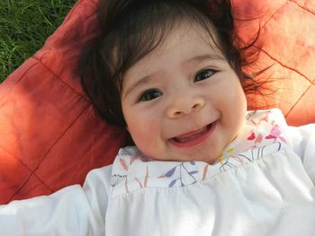 Portrait of cute girl lying on towel on grass outdoors