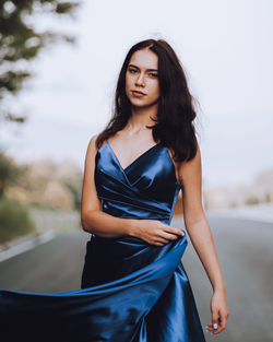 Young woman in blue dress standing on road