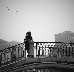 Side view of woman standing by railing against sky