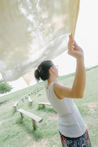 Side view of young woman holding shawl during windy day