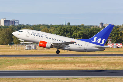 Side view of airplane on airport runway against sky