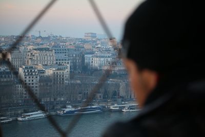 Rear view of man looking through the eiffel tower fence