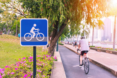 Man with bicycle sign on road in city