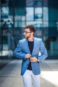 Young man wearing sunglasses standing against city