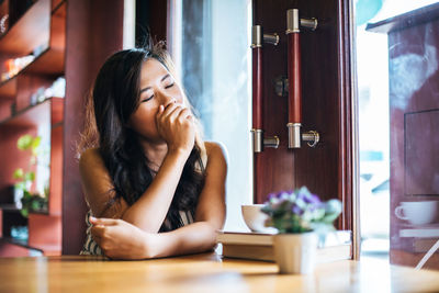 Woman looking away while sitting on table