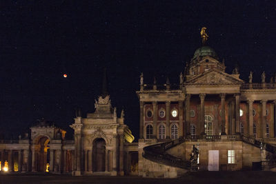 Statue in city against sky at night