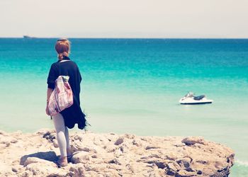 Rear view of man standing on shore against clear sky